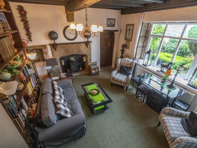 A beamed living room with stone fire surround and lovely views through the window.