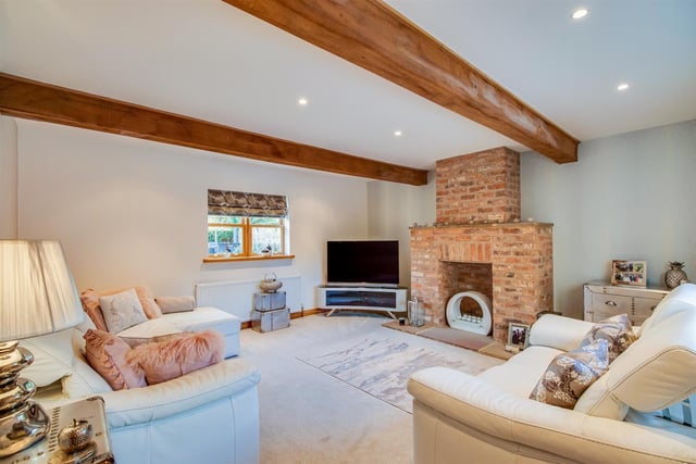 Wooden ceiling beams and a brick feature fireplace with chimney breast bring a rustic element to this comfortable sitting room.