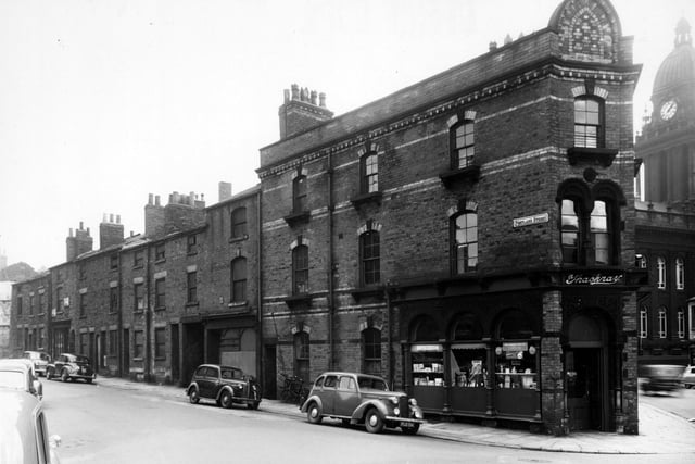 Looking along the south-east side of Portland Street in September 1954. Thackray's chemists is visible to the right. Cars are parked along the road. A bicycle with basket is leaning up against the wall. Leeds Town Hall is visible in the back right.