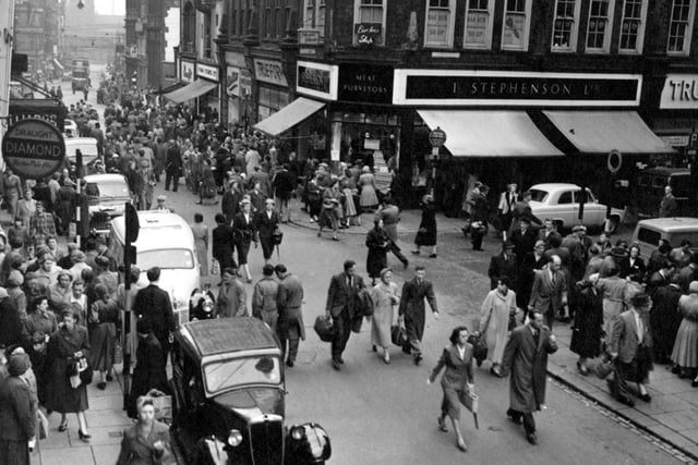 Looking south east along Kirkgate from Central Road in July 1956. I. Stephenson Ltd. butcher, J. Sears and Co. (True Form Boot Co.) Ltd. boot and shoe dealers, Chic Modes Ltd. ladies outfitters, Farm Stores Ltd. pork butchers and the Yorkshire Penny Bank shown.