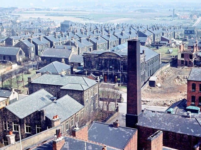 A view from Morley Town Hall Tower looking north-east towards Leeds, though nothing beyond the pit tip at Churwell is really visible. In the foreground are Morley Public Library and part of Morley Co-op's warehouse department with the chimney helping to supply the whole Co-op complex with central heating. Across the other side of Commercial Street is the Sunday School building for St. Mary's-in-the-Wood church and to the right of this Brighton Square has just been demolished along with houses at the end of Marshall Street just beyond. Pictured in April 1965.