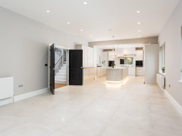 The kitchen opens onto the spacious dining area with windows and French doors opening onto a terraced patio area overlooking the mature gardens beyond.