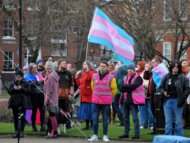 A transgender Pride flag is held aloft during the vigil.