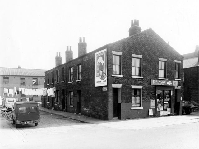 Eastwood Street and Cross Stamford Street pictured in September 1959. On the left of the image are three back-to-back terraced houses with a row of shared outside toilets at the far end between number 6 and Firth Terrace. Clothes are visible hanging on lines to dry, stretched across the street. On the right are numbers 40 and 42 Cross Stamford Street. On the side wall of number 42 is a large advertisement for Nestle's Cream. Number 40 on the right is M. Neary, family grocer. This area was locally known as Newtown.