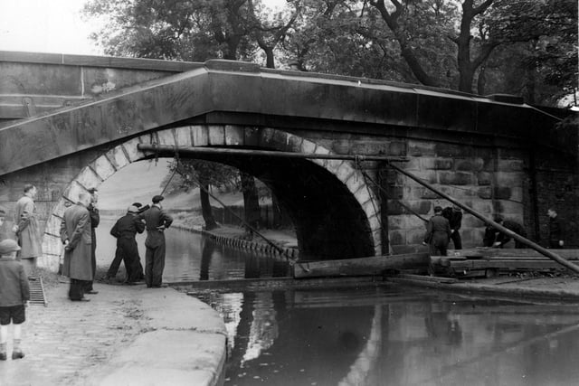 Redcote Bridge over the Leeds & Liverpool Canal. A demonstration of fixing a canal 'boom' by workmen in boiler suits is in progress, watched by two men and two children to the left. Pictured in September 1942.