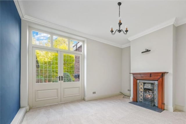 A period fireplace and wide double doors are lovely features within this ground floor room.