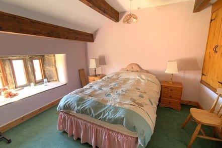 Beams and mullion windows with a deep window ledge add to the appeal in this bedroom.