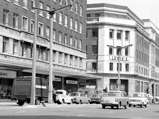 This view from June 1967 looks across The Headrow from the junction with Albion Street. To the left is Headrow House with shops on the ground floor including B.O.A.C. at number 34 and Vallance's radio and television engineers. On the right is Lewis's department store. Originally Woodhouse Lane continued from Merrion Street, running between these two buildings to join The Headrow. The area was later widened to accommodate the St John's Centre and Dortmund Square.