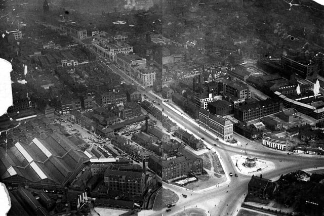This view looks west along The Headrow from Appleyard of Leeds Ltd on Eastgate roundabout. Kirkgate Market is visible to the left. Town Hall and Civic Hall can just be seen at top of picture. Old buildings on south side of Eastgate are still standing.