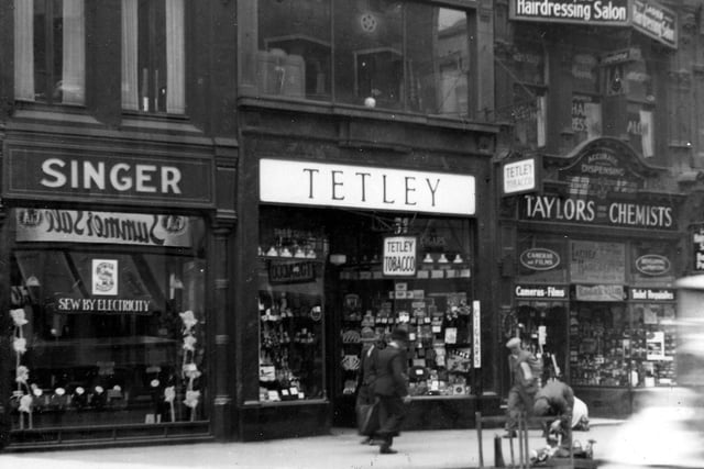 Shops on Boar Lane in June 1938. Pictured, from left are Singer Sewing Machines, Tetley Tobacconists and Taylors Chemist. Above Taylor's is a ladies hairdressing salon.