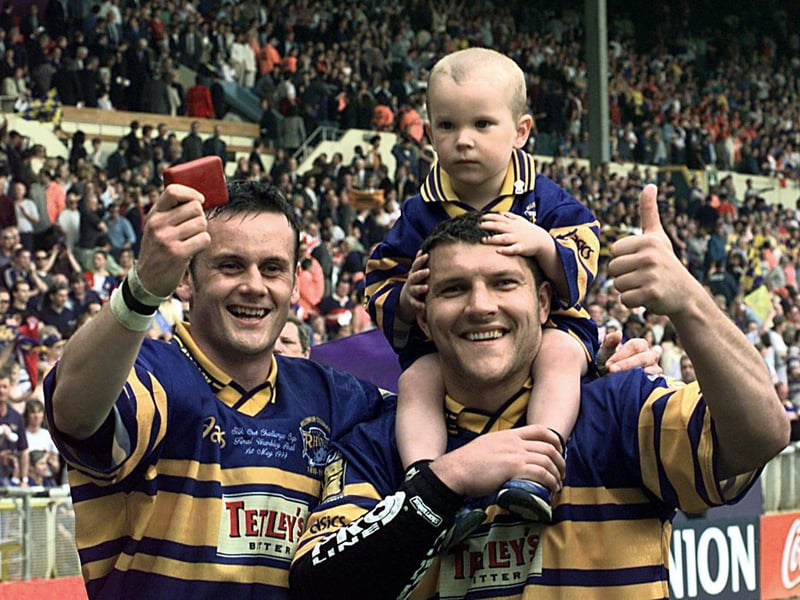 Try scorers Francis Cummins, left and Barrie McDermott celebrate with McDermott's son Billy, who was Rhinos' matchday mascot.
