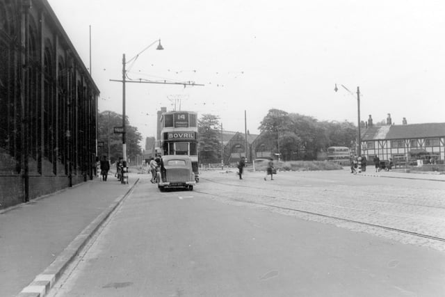 Stanningley Road looking towards Bramley Town End roundabout in July 1942. In the background are mills, mill chimneys, trees, Bramley National School (junior department) Good Shepherd School, half-timbered buildings and a bus. In the foreground tramlines, stone sets and a grating can be seen.