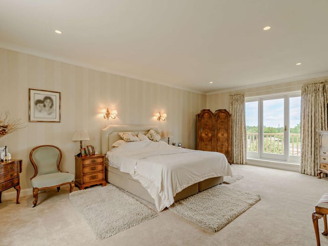 Doors lead out to a balcony from this luxurious bedroom.