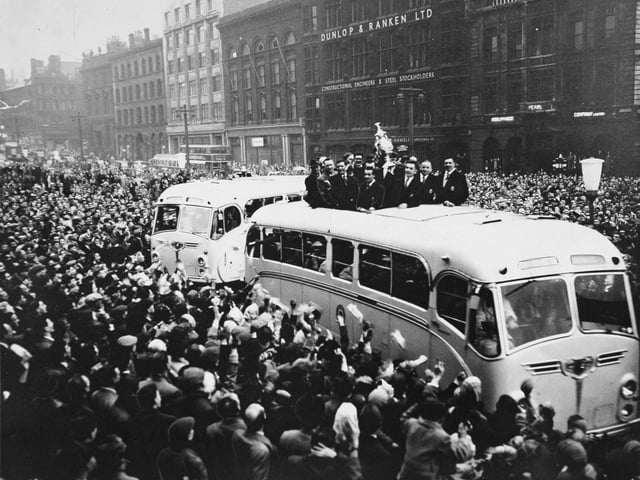 Through cheering crowds, a coach brings the Leeds Rugby League players and the Challenge Cup they won to Leeds Town Hall in May 1957. They beat Barrow 9-7 at Wembley in front of a crowd of 76,318.