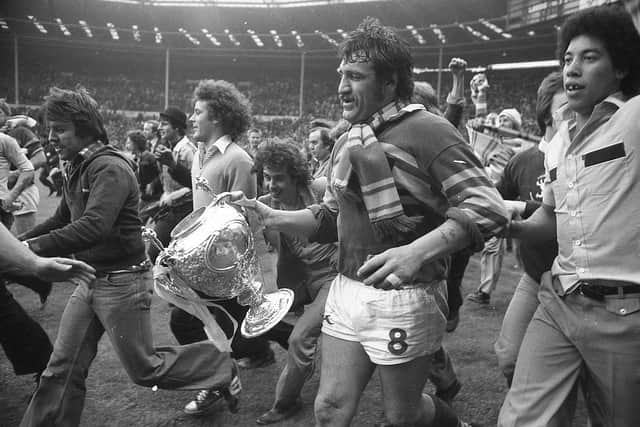 Mick Harrison, accompanied by jubilant Leeds fans, takes the Challenge Cup on a lap of honour at Wembley in 1978. Picture by Steve Riding.