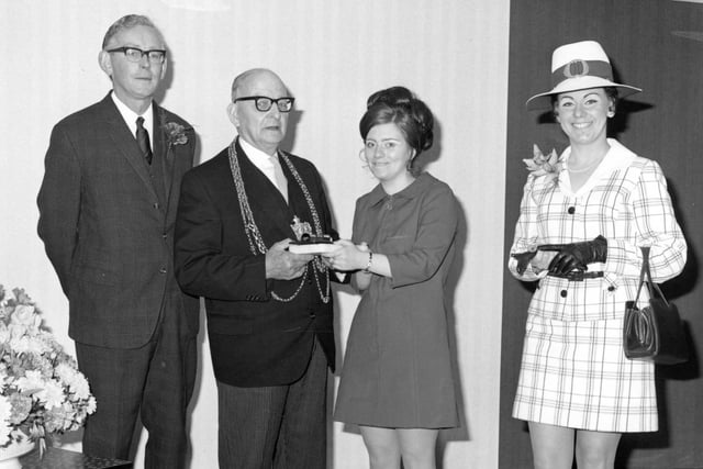 The reopening of Littlewoods store on Briggate after rebuilding in May 1970. Sales assistant Andrea Dowson is seen presenting Alderman Arthur Brown, Lord Mayor of Leeds, with an onyx deskset inscribed to commemorate the opening. Store manager Robert Bruce and Ida Bailey, who held the title of 'Miss Littlewood', are photographed with them.