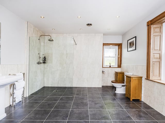This palatial bathroom has a walk in shower, twin wash basins and a stand alone bath.