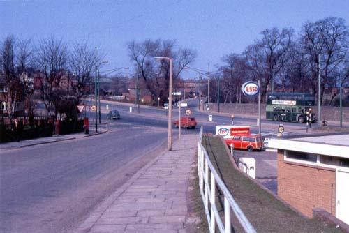 A view looking along Armley Ridge Road to where it crosses Stanningley Road in April 1969. Armley Grange Avenue is to the left, an ESSO petrol station is to the right. A green no.14 bus is on Stanningley Road.