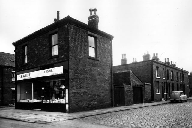 Temple View Road in July 1963. On the far left is the HR White Meat Perveyors, with the CH Gamble Pork Butchers on the right. Behind these shops on Berking Mount are yard entrances and a shared outside toilet block. On the far right of the image is Berking Mount.