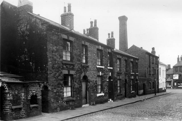 This view looks along the even numbered side of Grange Street in the direction of Wellington Road in July 1959. On the left edge are the entrances to outside toilet blocks and middens. Numbers 10 to 4 Grange Street then follow to the right where the back of the Spotted Cow pub is visible complete with maltings chimney.