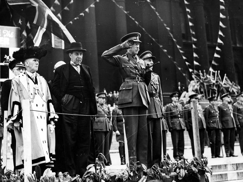The salute is being taken by Lord Harewood at the march-past at the beginning of the National Savings campaign. The opening ceremony was performed by the Chancellor of the Exchequer, Sir John Anderson, on the Town Hall steps, marking the first day's total of £1,614,658 on the indicator board there.