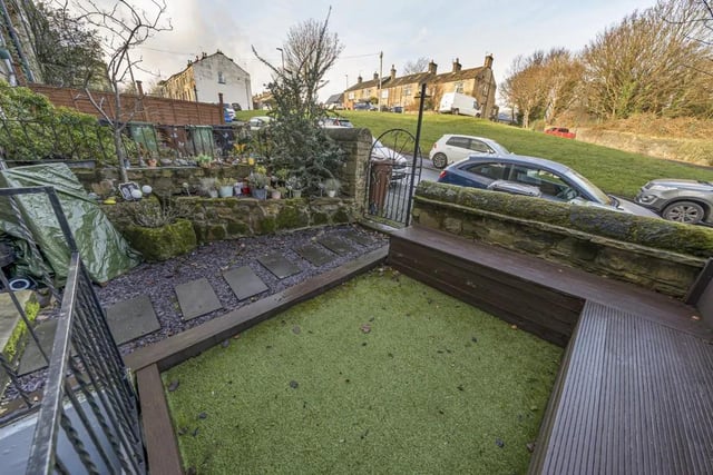 The garden features a low maintenance artificial grass lawn, raised beds to one side and built in seating at the other.
