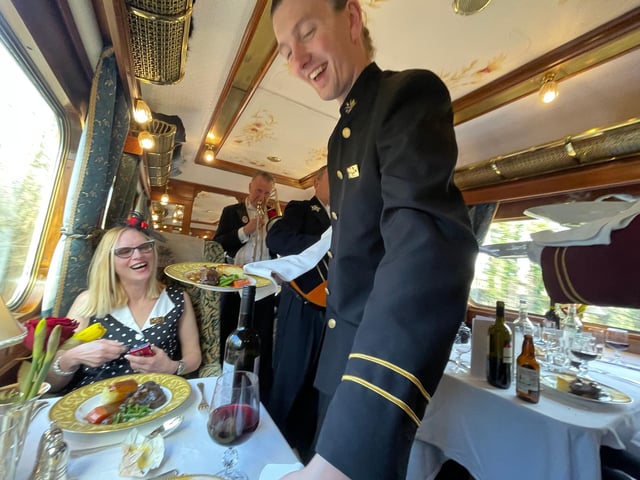 Music while you ear ...a waiter serves lunch while the train's resident musicians serenade passengers