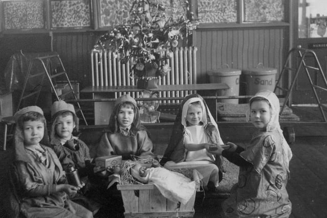 Pictured are children in a scene from a nativity play at Bentley Lane Infants in Meanwood in the 1950s. A doll representing baby Jesus lies in a small straw-filled crib, whilst three children dressed as the Wise Men are presenting gifts to two dressed as Mary and Joseph. A decorated Christmas tree can be seen in the background.