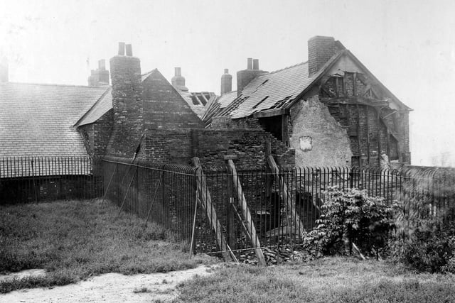 A view shows the back of an ancient and derelict building in Mabgate in September 1919. The wooden frame of the building can clearly be seen on the gable end with old brickwork beneath. The building, which could have dated from the medieval period, was due to be demolished. Iron railings surround the property, and grass and bushes can be seen in the foreground.