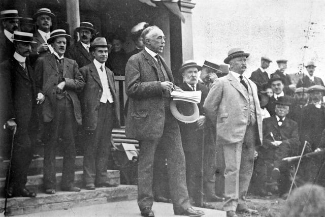 The former Town Clerk of Morley, Mr. R. Borrough Hopkins of Moor Allerton Hall, was invited to open the bowling green at the newly laid out Scatcherd Park. Here he is shown with his speech written out, entertaining the crowd at the opening, some of them being Morley Town Councillors; the present Town Clerk, Fred Thackray, is the middle of the three gentlemen behind him. On the edge of the steps in the light coloured suit is the Mayor of Morley, Alderman Samuel Rhodes, who introduced the guest speaker and then christened the bowling green by playing the first game of bowls against him. This would have been difficult wearing the Mayoral chain so it has been dispensed with on this occasion.
