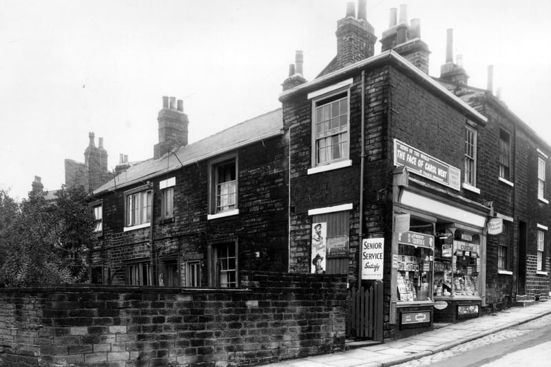 On the left here is Woodhouse Cliff. The first cottage in from the left is no.32, then 33 is next to the shop. This is no.7 Delph Lane, a newsagents and sweet shop. On the right is 9. Pictured in September 1959.