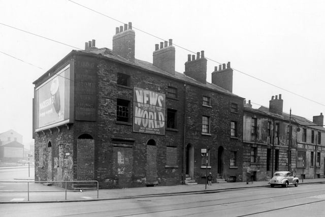 Wellington Street and the corner of Westgate in June 1953. There are derelict two and three storey buildings, one with a car outside. Advertising boards are visible for News of the World paper, Mackesons Beer and H. Cohen & Co. have a premise to right, wholesale clothiers