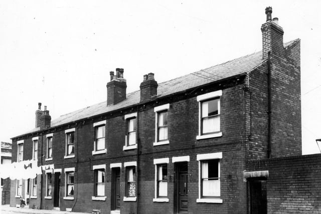Four double fronted blind back terraced houses with Lom View on the left and a yard on the right originally built to house the shared outside toilet. Two children are stood in the doorway of no.8 while clothes are hung out on lines streached across the street overhead. These houses were soon to be demolished under a Leeds City Council slum clearance programme. Pictured in August 1963.