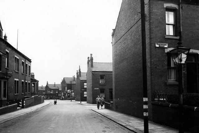 Looking east along Rowland Road in August 1949. On the right a gas street lamp is prominent. Behind it are the junctions with Westbourne Mount, Bude Road and Clovelly Row. A telephone pole with blackout markings and two people are on the pavement. On the left, number 36/38 is Rowlands Road Working Men's Club & Institute. Two children play in the road.