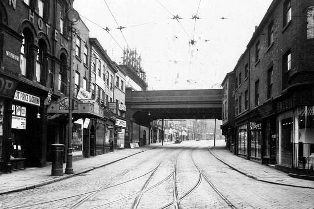 A view looking from the junction of Briggate with Call Lane (right) and Swinegate (left) through the London and North Eastern Railway bridge on Lower Briggate in June 1933. The Golden Lion Hotel can be seen on the left with Fred Verity and Son, Ironmongers on the right.