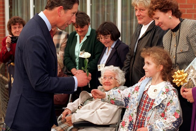 Prince Charles receives a carnation flower from six-year-old Anna Mitchell  after his visit around the Prince of Wales Hospice in October 1996.