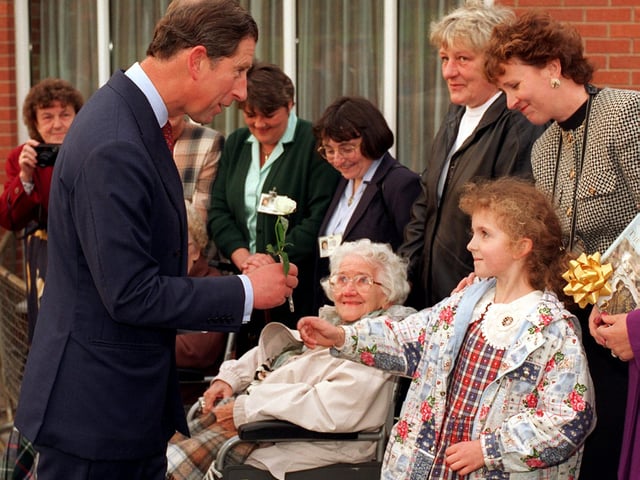 Prince Charles receives a carnation flower from six-year-old Anna Mitchell  after his visit around the Prince of Wales Hospice in October 1996.