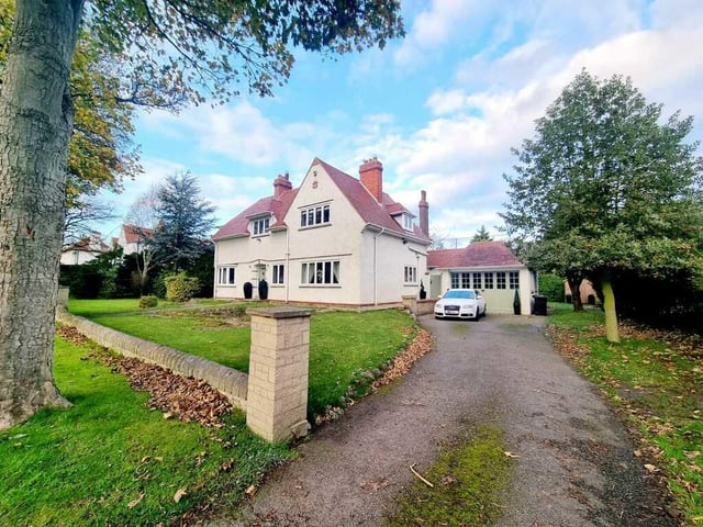 The house is set well back from the road, with driveway parking and a double garage.