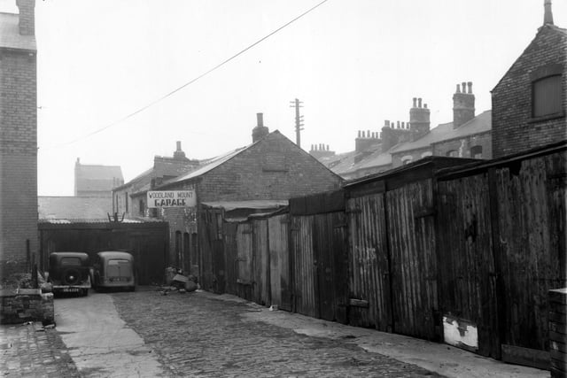 Garages belonging to the Woodland Mount Garage which was based at 11 Woodland Mount off Spencer Place. This view looks along Queen's Place. Pictured in February 1961.