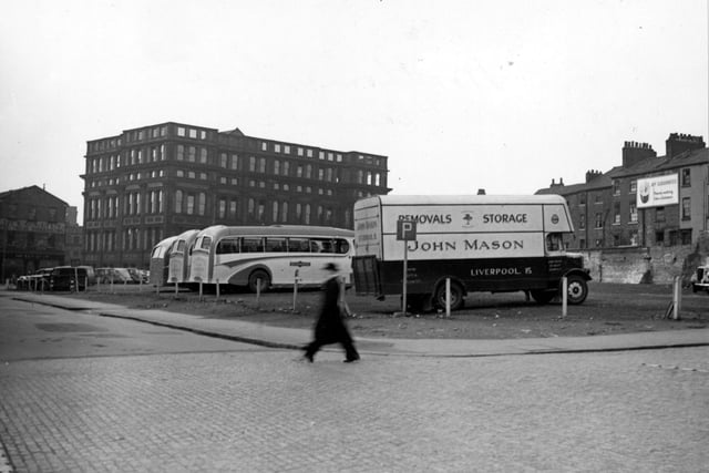 The junction of Wade Lane and Merrion Street, towards Woodhouse Lane, where the Central High School can be seen. In the foreground is a car park with a John Mason removal van and several coaches in it. An advertisement for Guinness is on the far right. Pictured in March 1948.