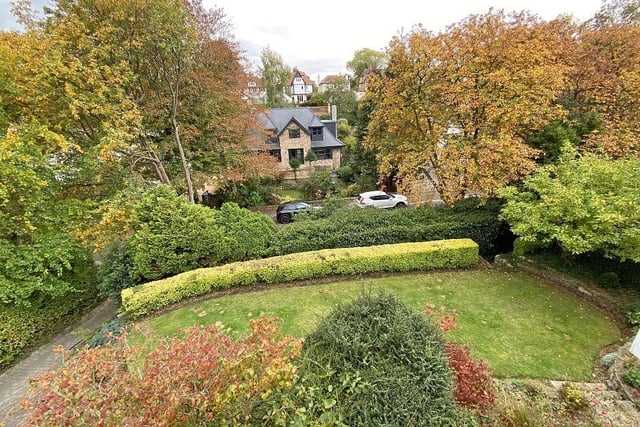 A lawned garden has established trees, shrubs, and hedging to the front of the property.