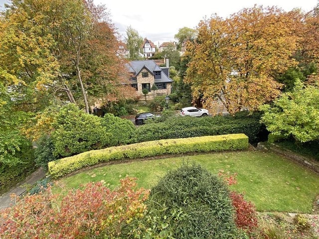 A lawned garden has established trees, shrubs, and hedging to the front of the property.