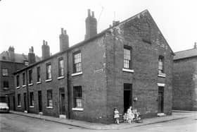 Barstow Street seen from Church Cross Street in June 1959. Two houses on Church Cross Street, number 4 has a cluster of children in the doorway, a woman is sat with them. To the right is 2 which is at the corner with Orfeur Street.