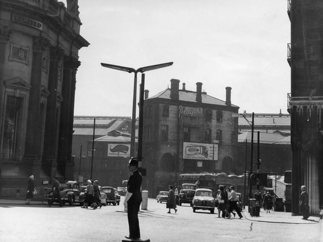 A police officer directs the traffic in Boar Lane in June 1959 at the busy junctions with Bishopgate Street where cars are visible towards the left, and Wellington Street, far right.