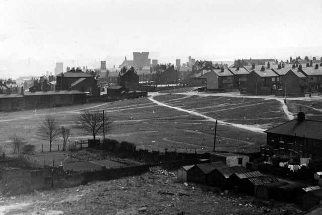 This view looks east across waste/recreation ground to houses at the top of Parliament Road, with beyond them the Abbotts and the Winchesters and in the background centre, Armley Jail. In the background right are Model Avenue and Model Road and behind them Holy Family R.C. School, while in the foreground on the far right is the end of a block of houses on Nancroft Terrace with a row of garages in front.