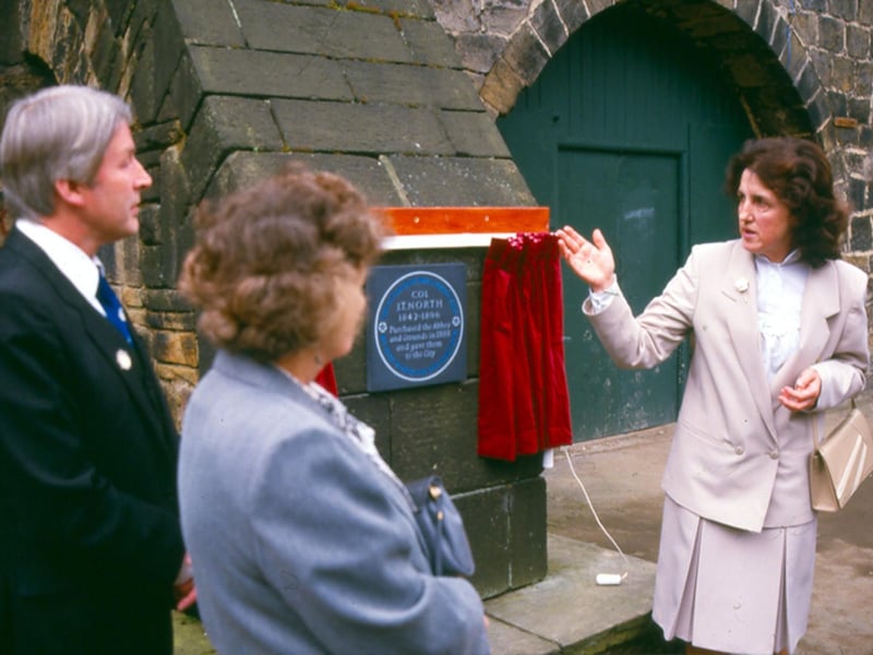 The unveiling of a plaque commemorating Colonel John Thomas North (1842-1896) in recognition of his gift of Kirkstall Abbey to the City of Leeds. It reads 'Colonel J.T. North 1842-1896 purchased the Abbey and grounds in 1888 and gave them to the city.' In blue letters around the circumference it states 'This plaque was put up by the Yorkshire Society'. Pictured in August 1990.