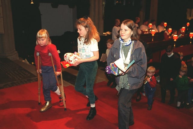 Children make their way forward to place gifts under the Christmas tree at the Yorkshire Evening Post Carol Service held at the Leeds Parish Church in December 1996.