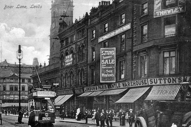 The north side of Boar Lane from a postcard with postmark September 27, 1907. On the right is Sutton's London & Paris Mantle Warehouse which is advertising a summer sale. Above this is the photographic studio of Arthur Thawley, who describes his products as 'Thawley's Good & Artistic Photos'. Further along are the premises of Mrs. Melbourne, costumier, then Holy Trinity Church. After the junction with Trinity Street is the Grand Pygmalion, the department store owned by Monteith, Hamilton & Monteith Ltd.