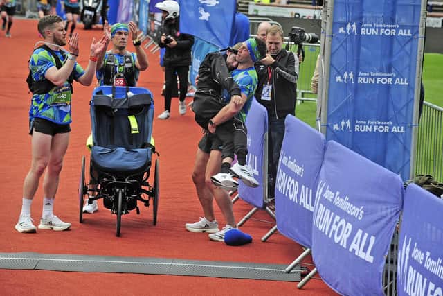Kevin Sinfield lifts Rob Burrow over the finish line of the Rob Burrow Leeds Marathon in 2023. Picture by Steve Riding.