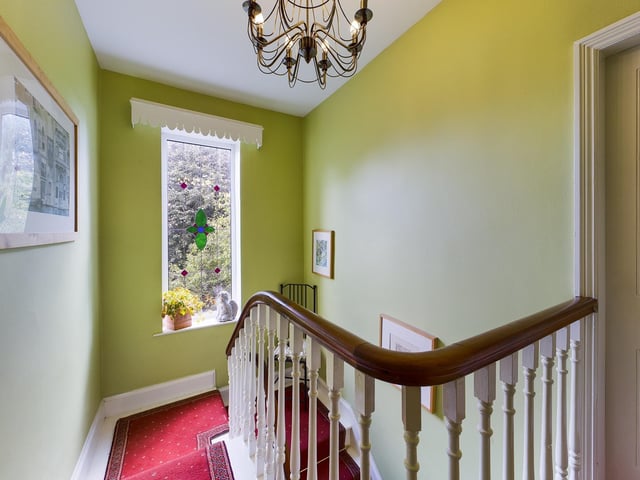 An original spindle staircase and gallery landing lit by a stained glass window.